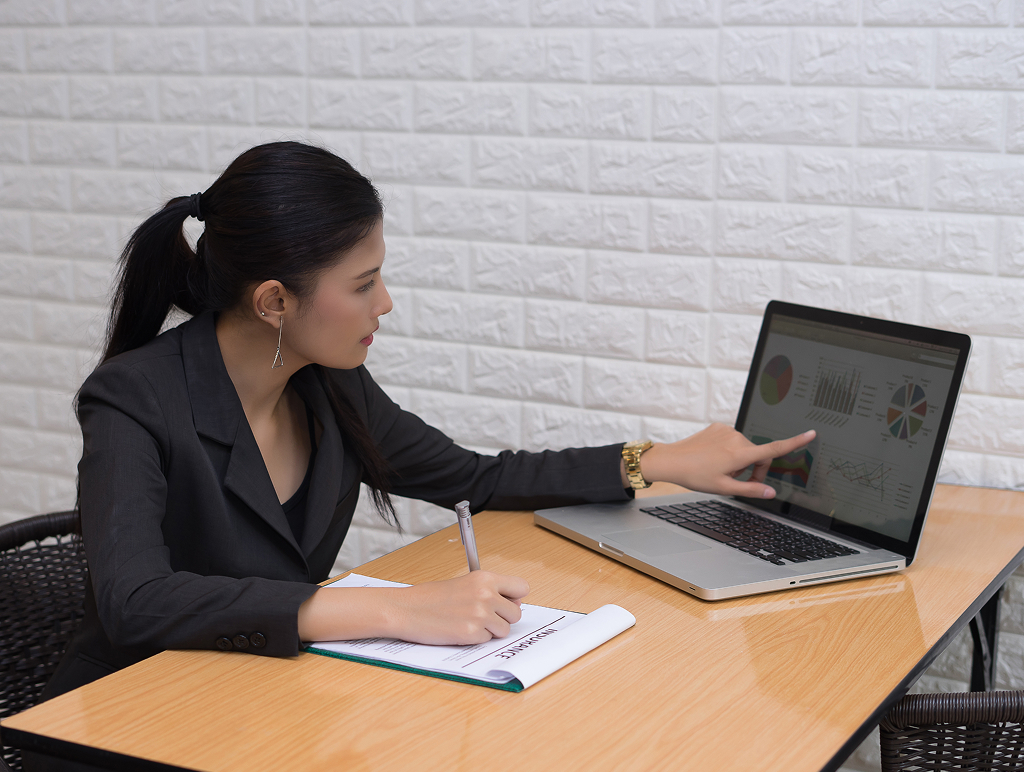 Young business woman reviewing documents at an office desk — offshore administrative role